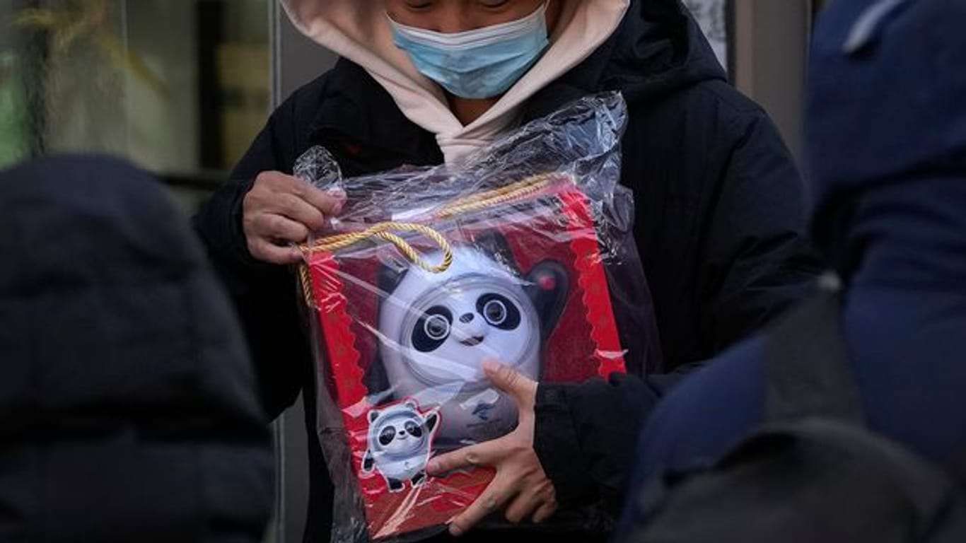 Ein Mann hält die Puppe des olympischen Maskottchens Bing Dwen Dwen in der Hand, die er in einem Geschäft in Peking gekauft hat.