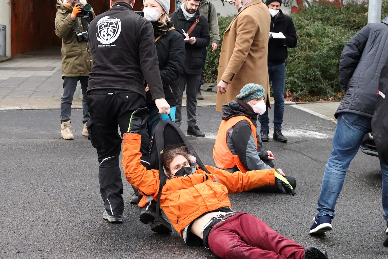 Ein Mann zieht einen Klimaaktivisten an seinem Rucksack von einer Straße: Seit Tagen sorgen die Klimaschützer für Verkehrschaos in der Hauptstadt.