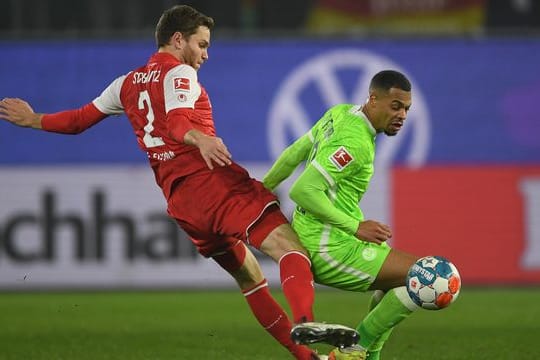 Wolfsburgs Lukas Nmecha (r) behauptet im Zweikampf gegen Kölns Benno Schmitz den Ball.