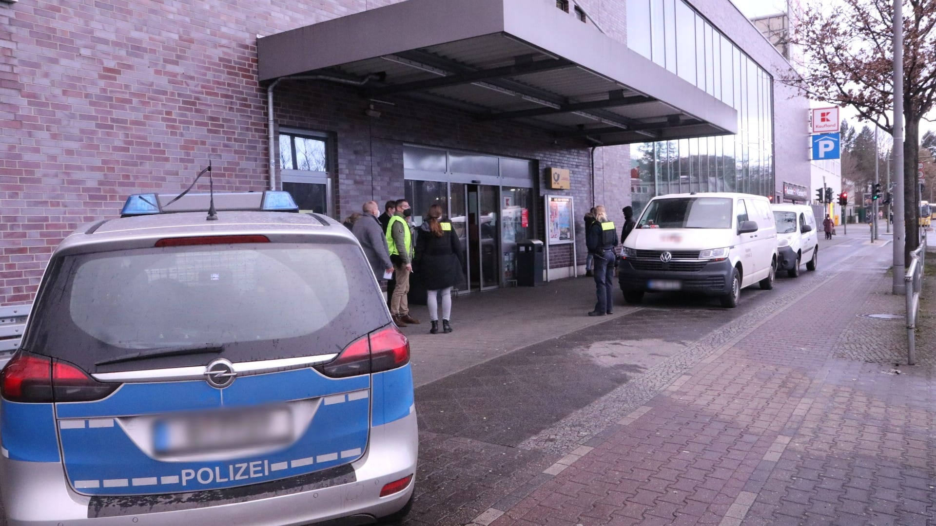 Ein Polizeifahrzeug, Beamte und Zeugen stehen vor dem Supermarkteingang und dem Geldtransporter: Die Täter sollen mit Reizgas gesprüht haben.