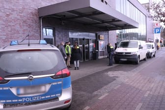 Ein Polizeifahrzeug, Beamte und Zeugen stehen vor dem Supermarkteingang und dem Geldtransporter: Die Täter sollen mit Reizgas gesprüht haben.