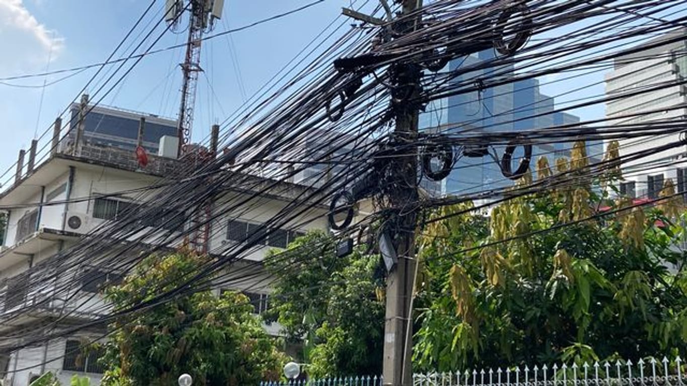 Strom- und Telefonleitungen werden in Thailand nicht unterirdisch verlegt, sondern spannen sich in massiven schwarzen Bündeln von Mast zu Mast.