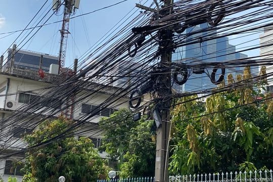 Strom- und Telefonleitungen werden in Thailand nicht unterirdisch verlegt, sondern spannen sich in massiven schwarzen Bündeln von Mast zu Mast.