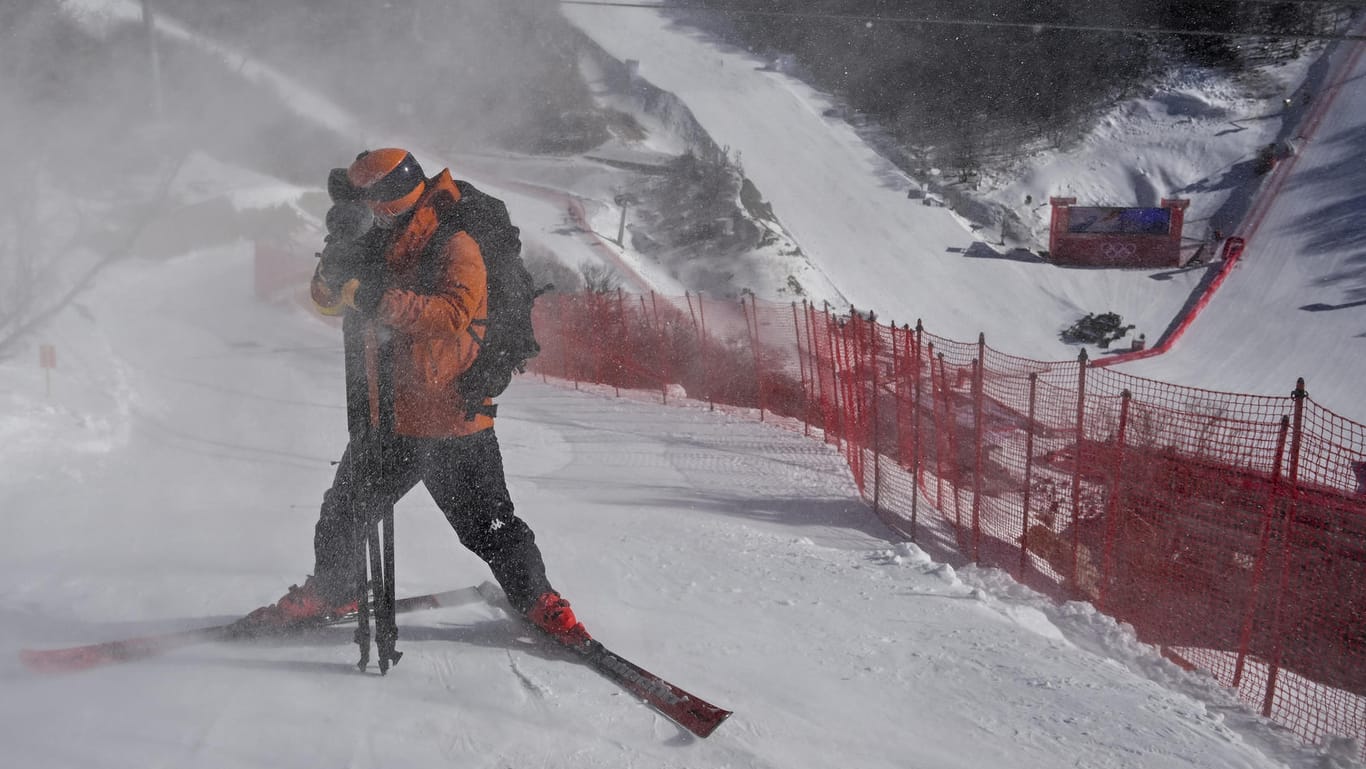 Ein Athlet schützt sein Gesicht vor wirbelndem Schnee (Symbolfoto): In Yanqing mussten die Abfahrtsstrecken bereits mehrfach gesperrt werden. Die Windgeschwindigkeiten waren teils auch für Trainingseinlagen zu stark.