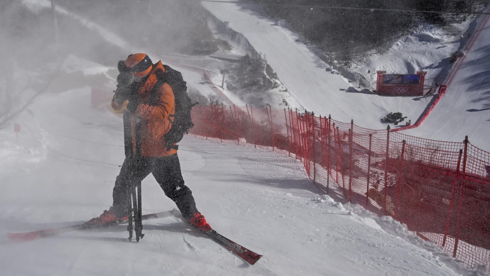 Ein Athlet schützt sein Gesicht vor wirbelndem Schnee (Symbolfoto): In Yanqing mussten die Abfahrtsstrecken bereits mehrfach gesperrt werden. Die Windgeschwindigkeiten waren teils auch für Trainingseinlagen zu stark.