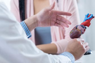 Arzt erklärt einem Patienten etwas anhand eines Herzmodells