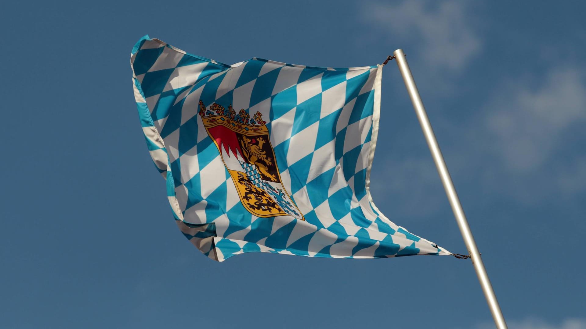 Landesflagge des Freistaats Bayern weht im Wind vor blauem Himmel in München.