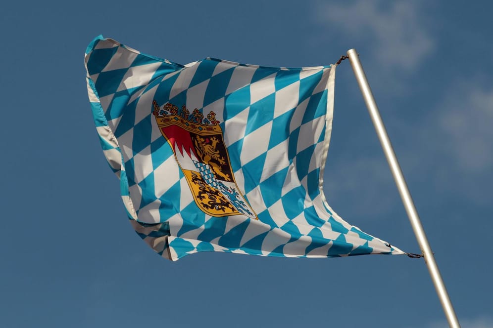Landesflagge des Freistaats Bayern weht im Wind vor blauem Himmel in München.