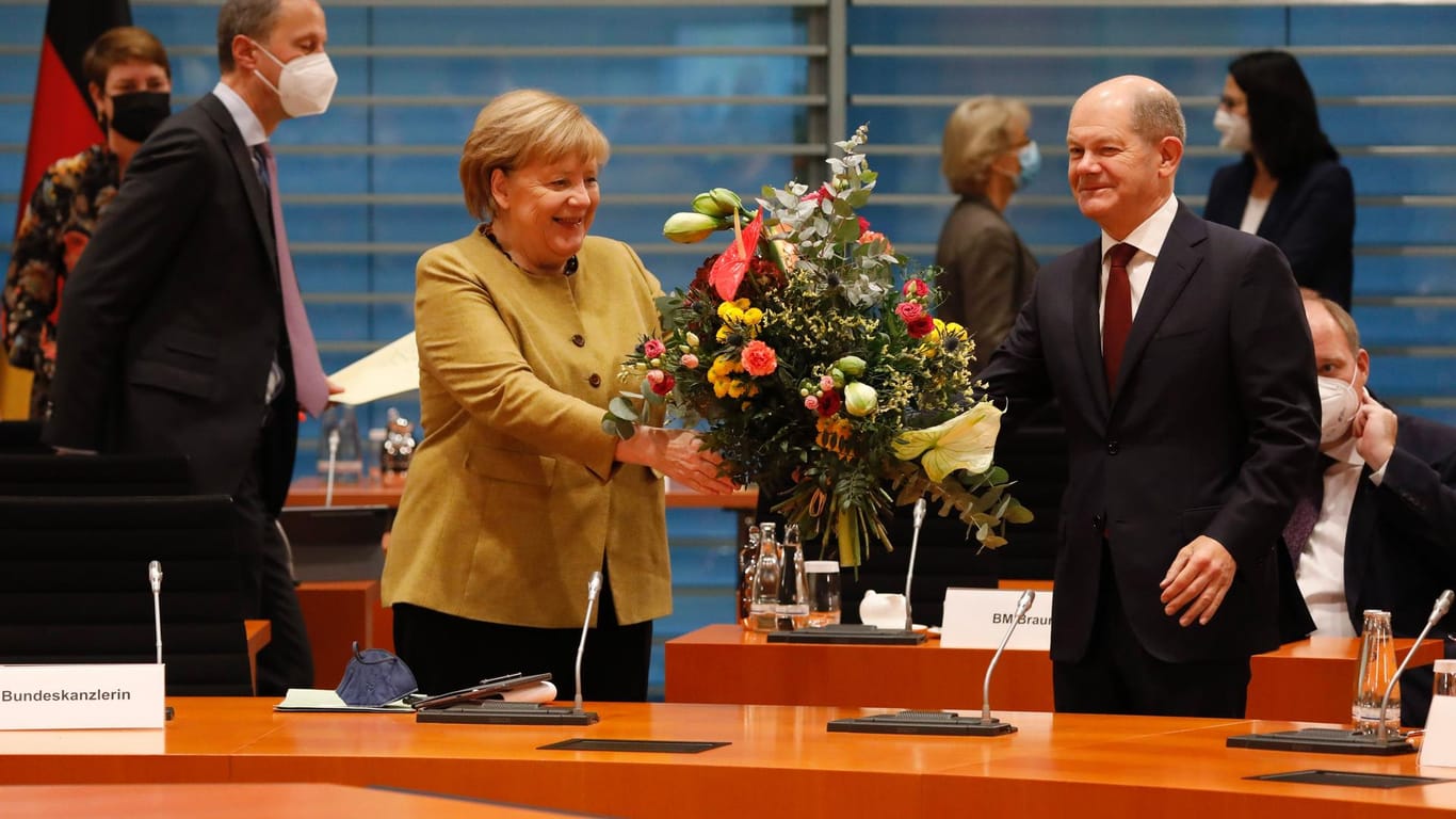 Ein Blumenstrauß auf die Kontinuität: Angela Merkel und Olaf Scholz im Kanzleramt.