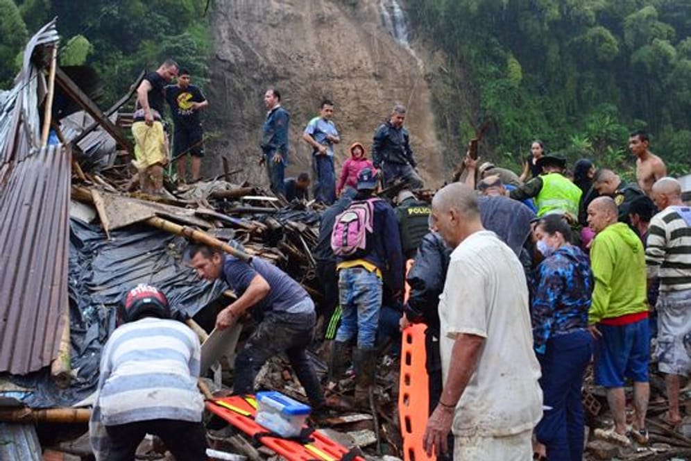 Rettungskräfte und Einwohner suchen zwischen den Trümmern der weggerissenen Häuser nach Überlebenden.