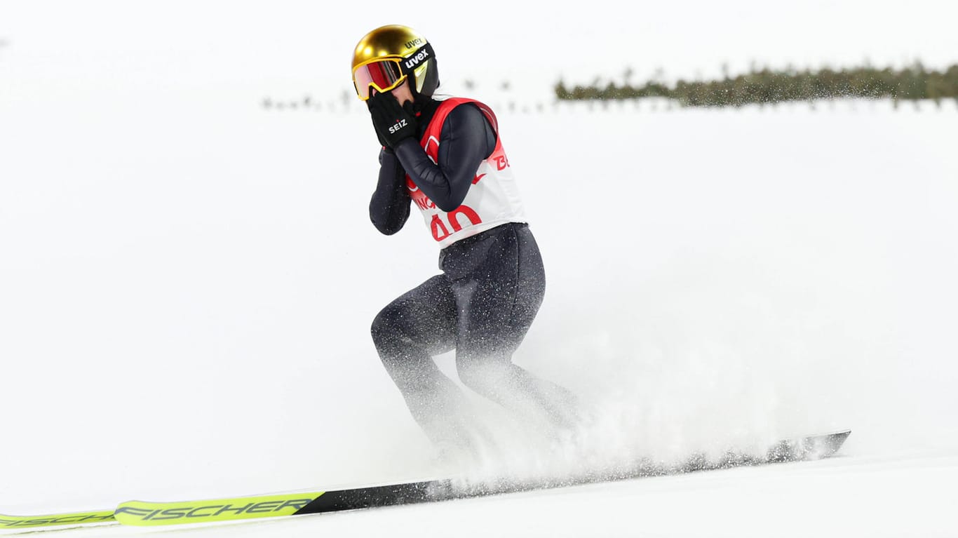 Anspannung nur bei der Sportlerin: Während Katharina Althaus nach ihrem Sprung um eine Olympiamedaille bangt, schwenkt das chinesische Publikum im Skisprungstadion unbeeindruckt seine Fähnchen.