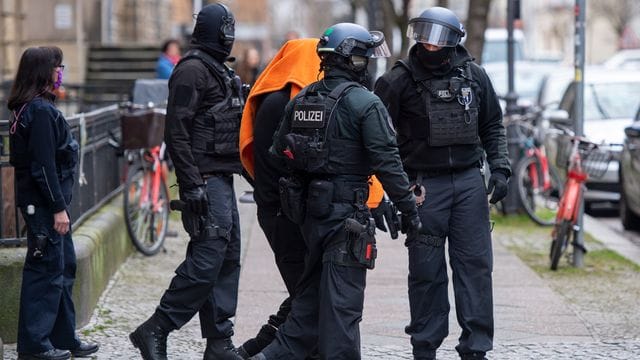 Polizisten bringen den Angeklagten unter einer Decke aus dem Gerichtsgebäude in Berlin. Polizisten bringen den Angeklagten unter einer Decke aus dem Gerichtsgebäude in Berlin.