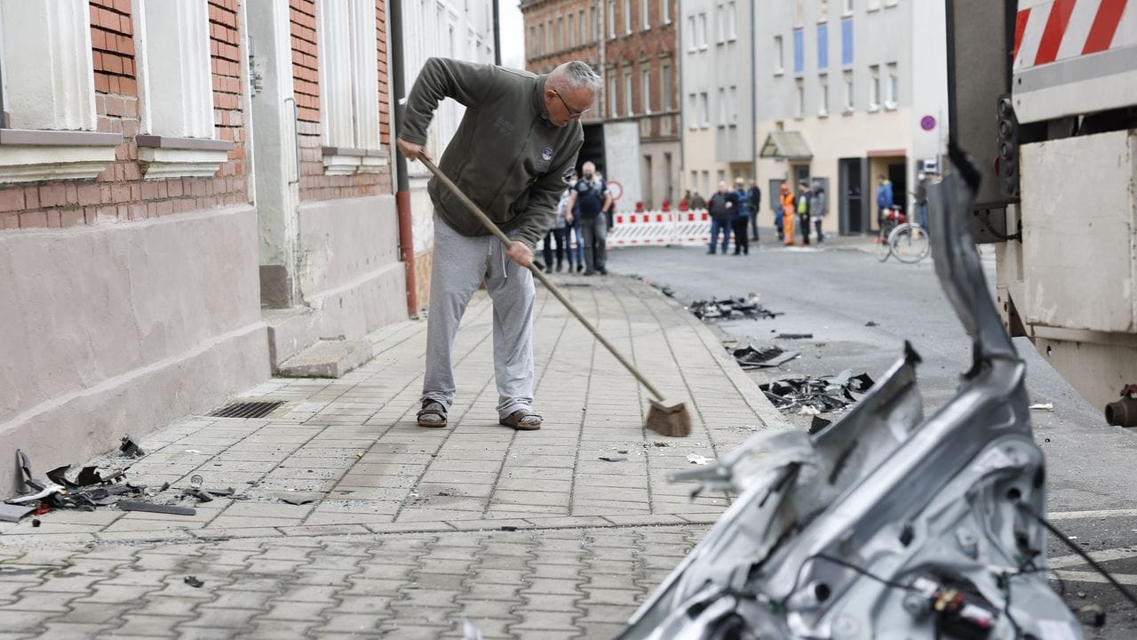 Ein Anwohner kehrt am Tag nach der Chaosfahrt den Bürgersteig vor seinem Haus.