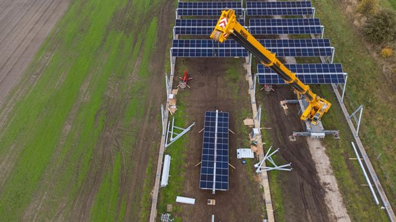 Mit einem Kran wird eine Agrar-Photovoltaik-Anlage in Niedersachsen montiert.