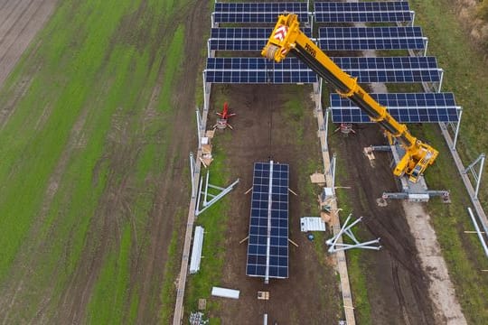 Mit einem Kran wird eine Agrar-Photovoltaik-Anlage in Niedersachsen montiert.