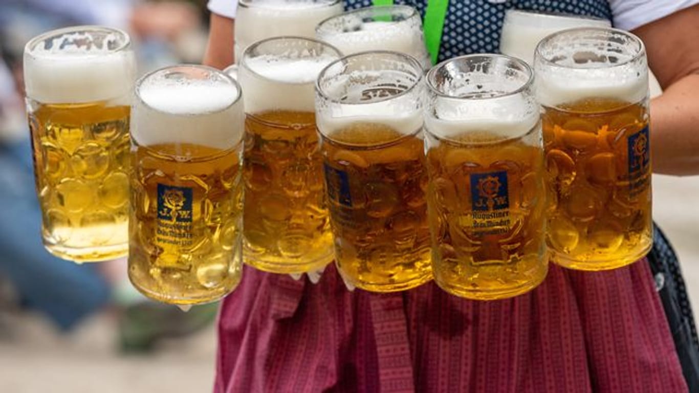 Eine Bedienung trägt acht Maß Bier zu Tischen