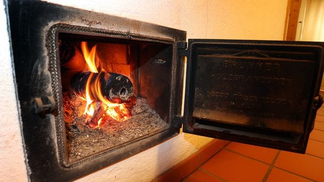 Ein Holzofen wird vom Hausflur aus mit Holzbriketts geheizt.