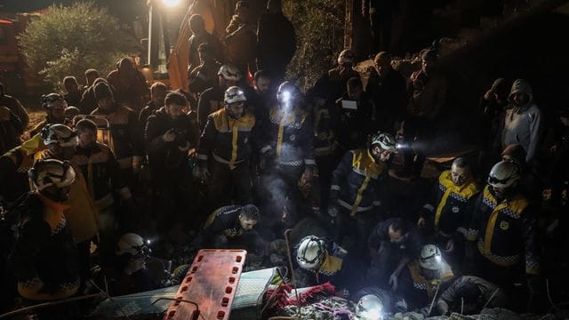 Mitglieder der syrischen Zivilverteidigung White Helmets versuchen, eine Familie aus den Trümmern eines zweistöckigen Hauses zu retten.