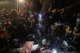 Mitglieder der syrischen Zivilverteidigung White Helmets versuchen, eine Familie aus den Trümmern eines zweistöckigen Hauses zu retten.