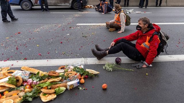 Klimaaktivisten der Gruppe "Aufstand der letzten Generation" sitzen auf der Fahrbahn und blockieren den Verkehr.