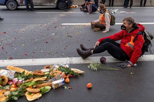 Klimaaktivisten der Gruppe "Aufstand der letzten Generation" sitzen auf der Fahrbahn und blockieren den Verkehr.