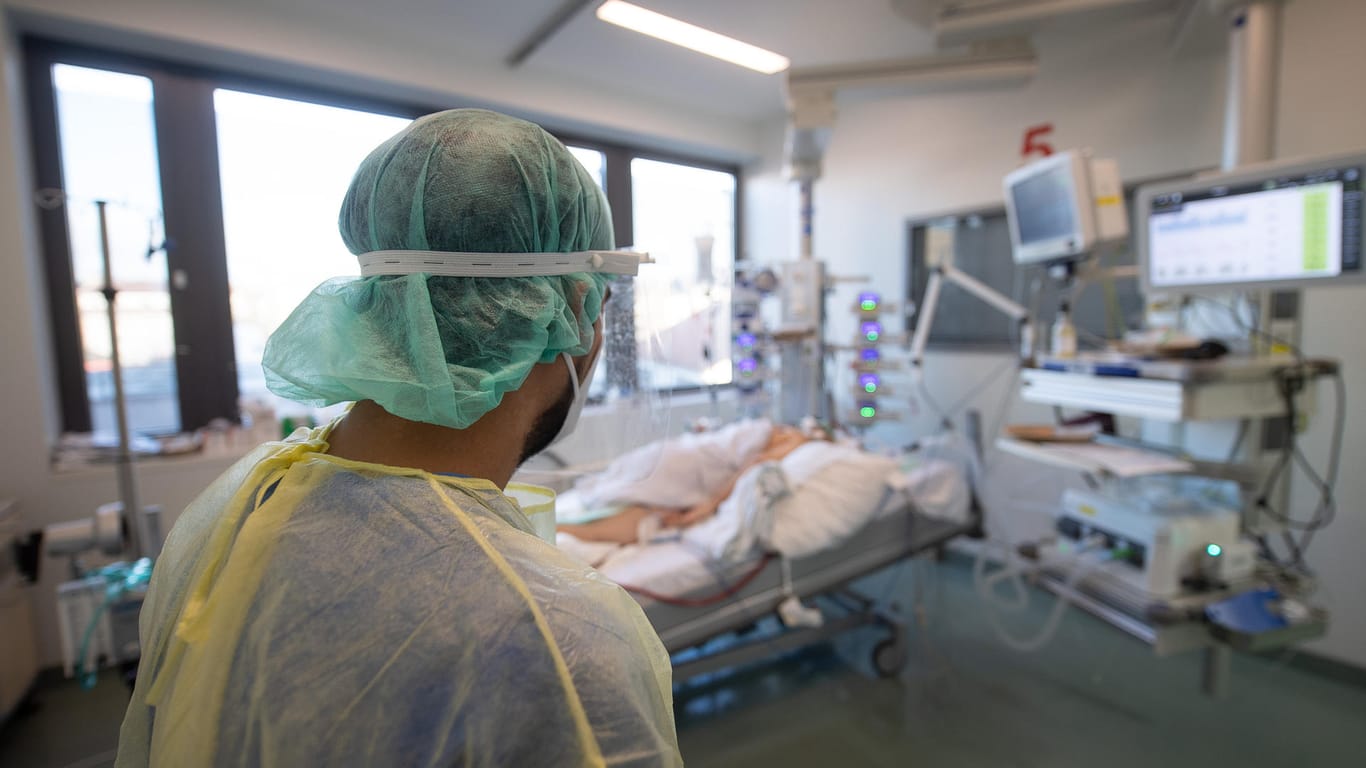 Ein Pfleger schaut auf einen Corona-Erkrankten (Archivbild): In Deutschland wurden vergangene Woche 2.398 Intensivpatienten gezählt.
