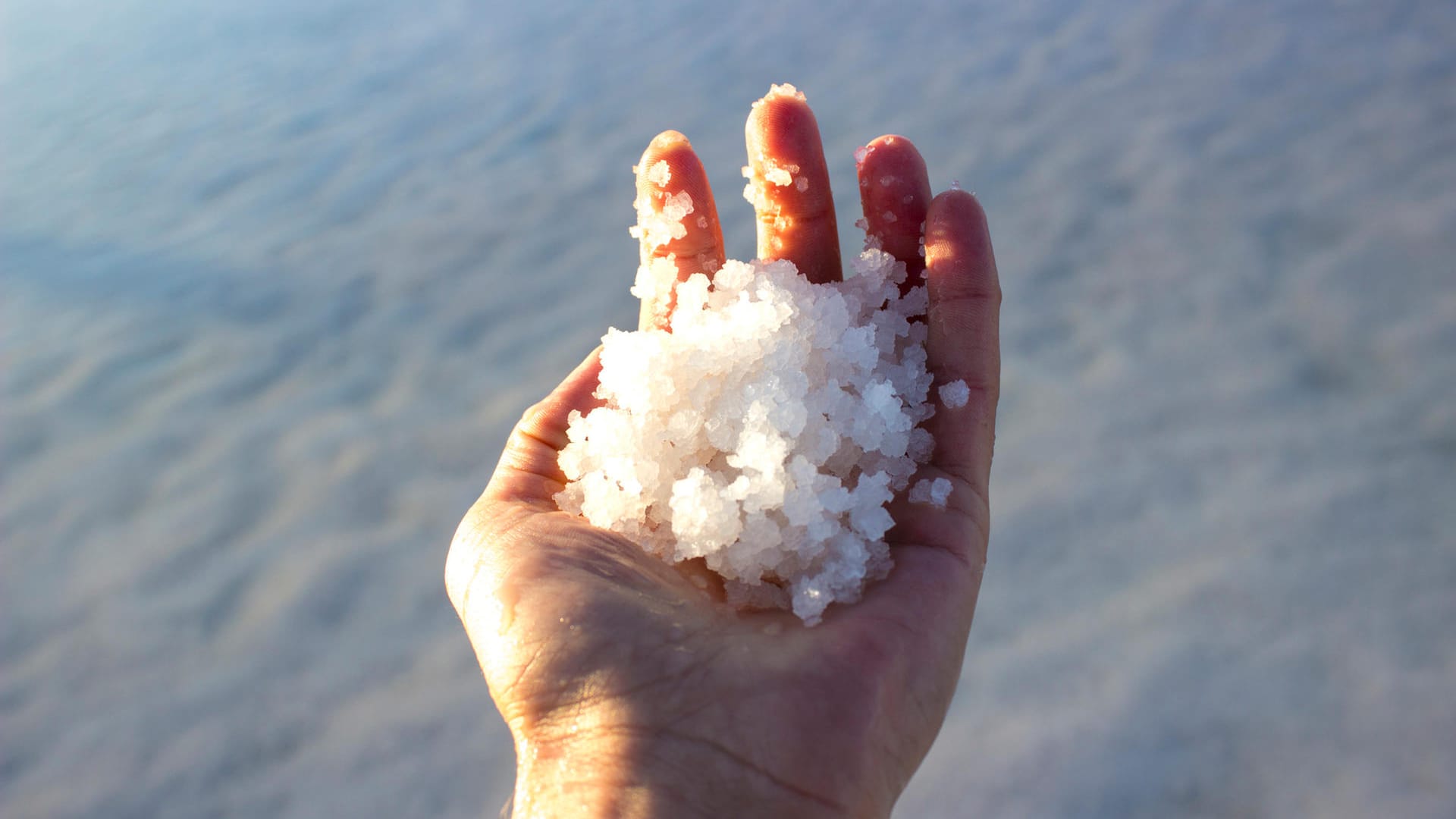 Man holding salts in salt lake in Aksaray, Turkey