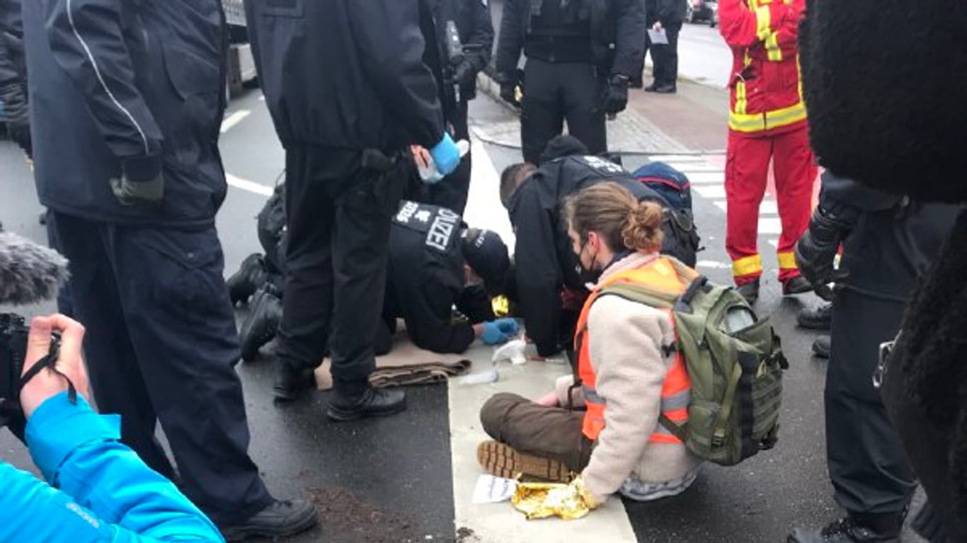 Polizisten lösen Demonstranten von der Fahrbahn ab, die sich dort festgeklebt hatten: Oft handelt es sich bei den verschiedenen Blockaden um dieselben Personen.