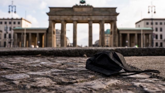 Eine schwarze Corona-Makse liegt auf dem Boden vor dem Brandenburger Tor. Eine schwarze Corona-Makse liegt auf dem Boden vor dem Brandenburger Tor.