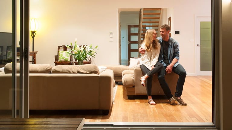 Ein Paar sitzt in seinem Wohnzimmer (Symbolbild): Je mehr Vermögen Sie selbst für den Hauskauf einsetzen können, desto günstiger die Finanzierung.