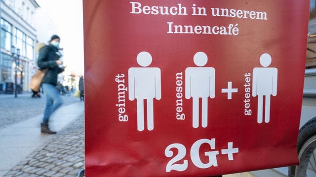 Ein Schild weist auf die 2G Plus Regel in einem Café im Ostseebad auf Rügen hin.