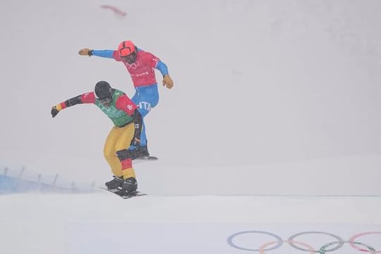 Snowboardcrosser Martin Nörl (l) rast beim Team-Wettbewerb über die Piste.