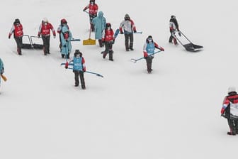 Helfer versuchen die Slopestyle-Piste vom Schnee zu befreien.