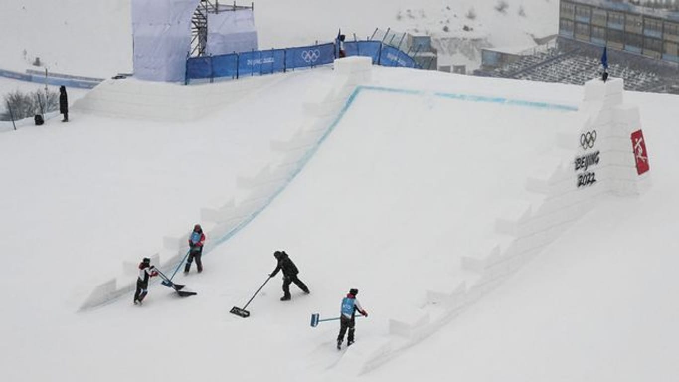 Helfer befreien die Freestyle-Strecke der Skier vom Neuschnee.