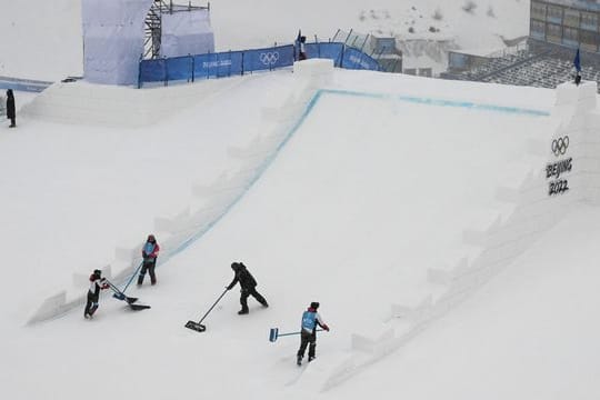 Helfer befreien die Freestyle-Strecke der Skier vom Neuschnee.