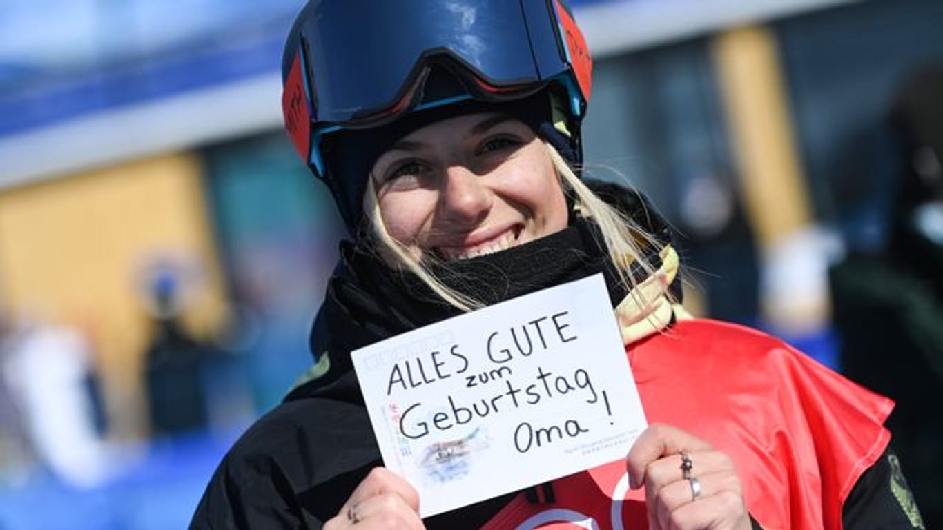 Aliah Delia Eichinger hält ein Schild mit der Aufschrift "Alles Gute zum Geburtstag Oma!" in die Kamere.