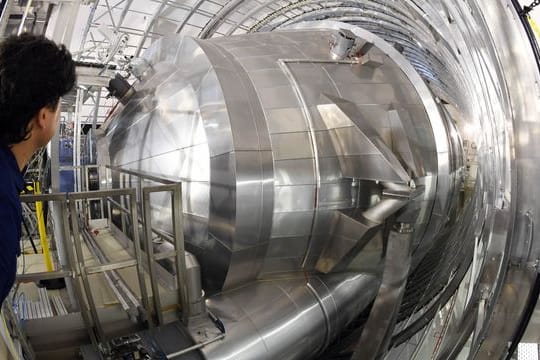 Ein Mitarbeiter des Karlsruher Tritium Neutrino Experiments (Katrin) am Karlsruher Institut für Technologie (KIT) blickt auf das Hauptspektrometer der Anlage.