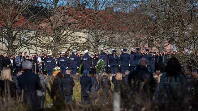 Trauergäste, darunter viele Polizisten, stehen am Grab bei der Beisetzung des Polizisten in Freisen.