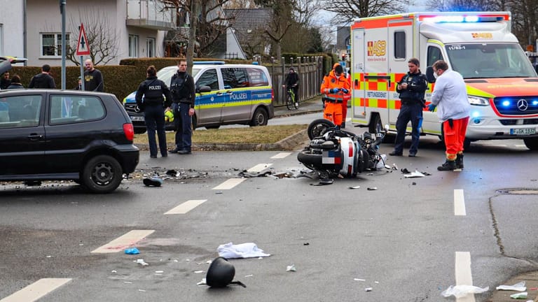 Spuren des Unfalls auf der Straße: Trümmerteile und ein Helm liegen neben dem schwer beschädigten Roller.