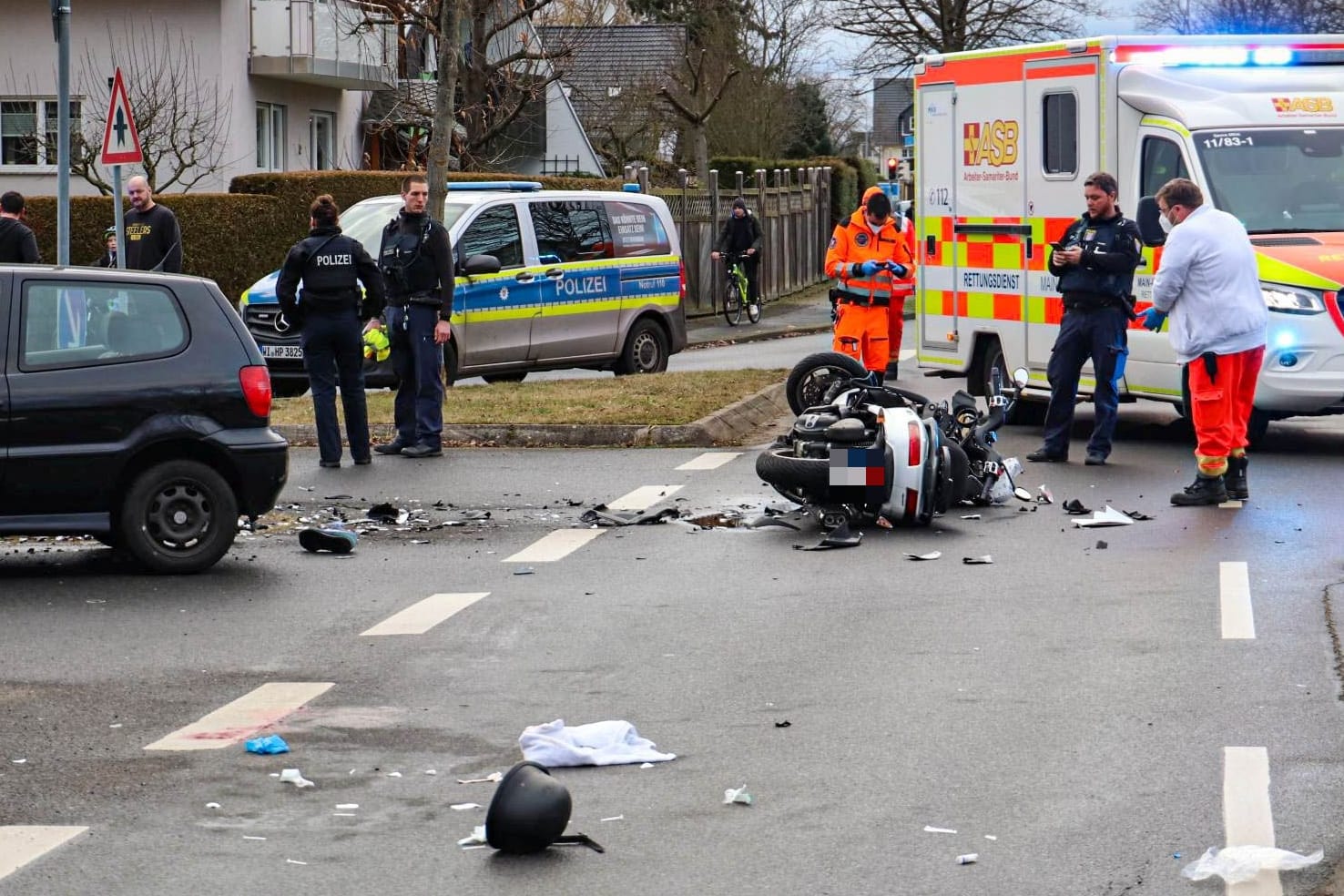 Spuren des Unfalls auf der Straße: Trümmerteile und ein Helm liegen neben dem schwer beschädigten Roller.