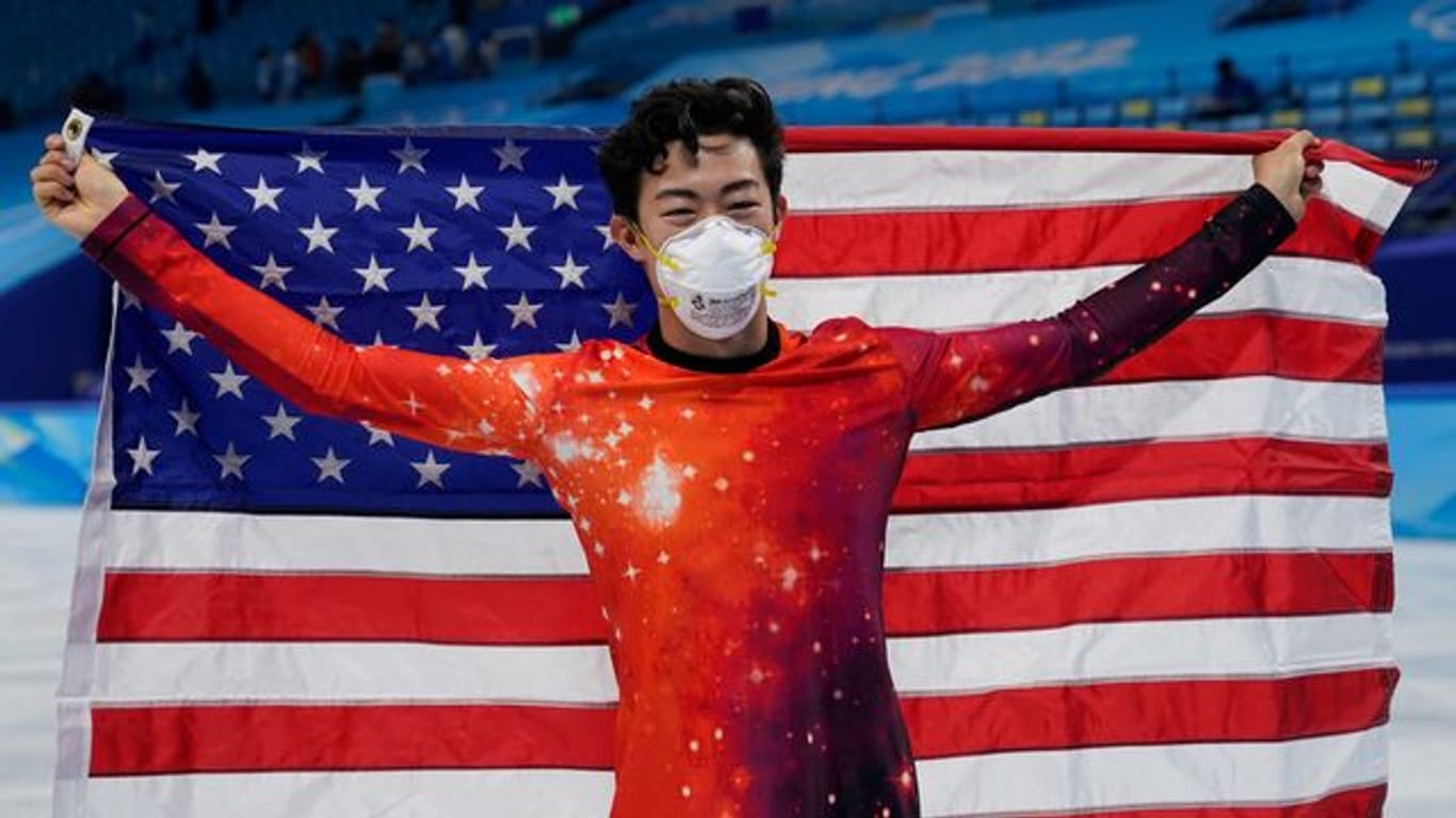 Eiskunstläufer Nathan Chen hält eine amerikanische Flagge hoch und freut sich über seinen Erfolg.