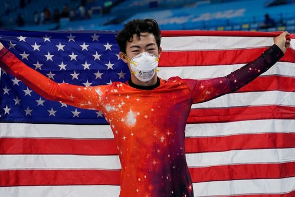 Eiskunstläufer Nathan Chen hält eine amerikanische Flagge hoch und freut sich über seinen Erfolg.