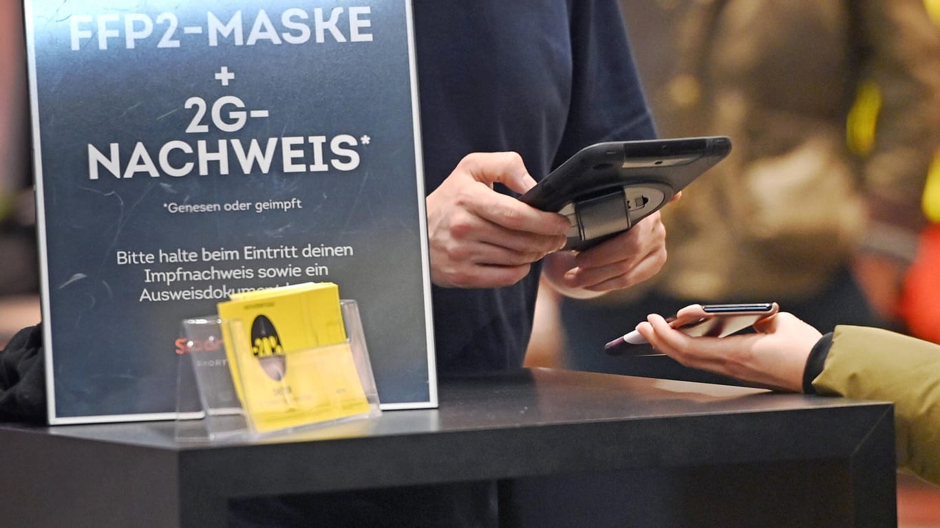 Eine Person scannt den 2G-Nachweis eines Kunden (Archivbild): Auch die Zugangsbeschränkungen werden in Bayern strikt gelockert.