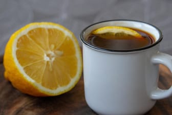 Tasse Kaffee mit einer halben Zitrone: Viele Kopfschmerzgeplagte schwören auf Kaffee mit Zitrone. Einen Versuch ist die ungewöhnliche Kombi wert.