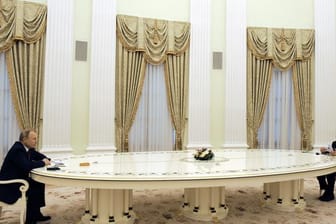 Russlands Präsident Wladimir Putin (links) und Bundeskanzler Olaf Scholz (SPD) sitzen sich an einem langen Tisch im Kreml gegenüber.