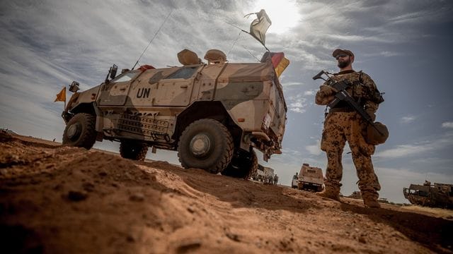 Ein Soldat der Bundeswehr steht in Mali neben einem Militärfahrzeug.