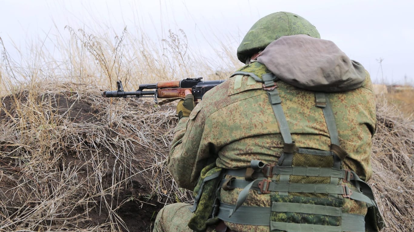 Ein ukrainischer Kämpfer kniet bewaffnet in einem Graben (Symbolbild): Jugendliche bereiten sich in der Ukraine auf den Kriegsfall vor und heben Schützengräben aus.