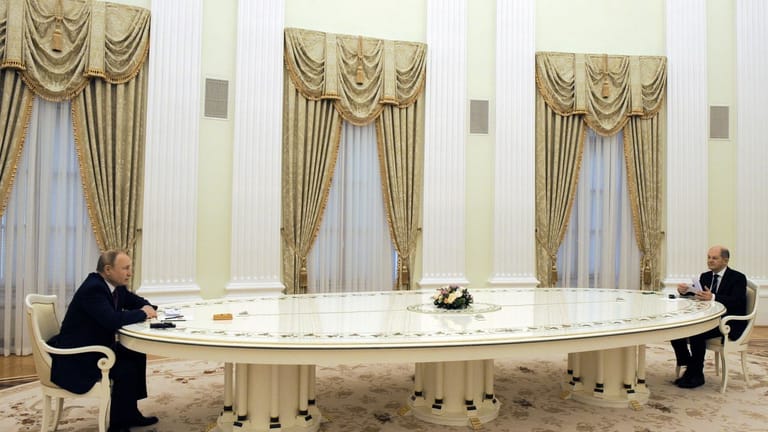 Russlands Präsident Wladimir Putin (links) und Bundeskanzler Olaf Scholz (SPD) sitzen sich an einem langen Tisch im Kreml gegenüber.