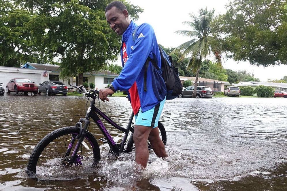 Ein Mann schiebt sein Rad durch Hochwasser in Florida (Archivbild): Die Nasa erwartet in den Küstengebieten mehr Überschwemmungen durch den Meeresspiegelanstieg.