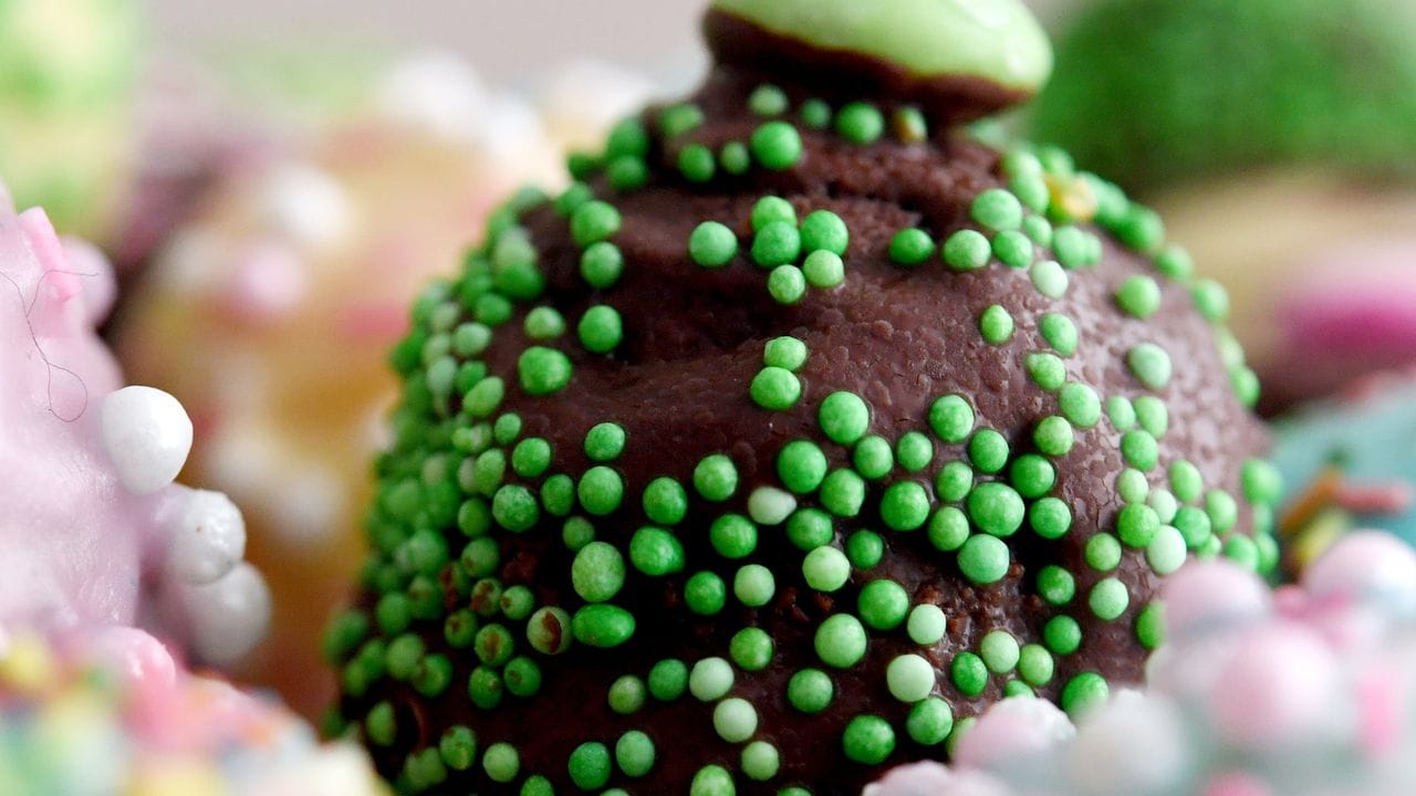 Die Cake-Pops werden in geschmolzene Kuvertüre getaucht und nach Fantasie mit Streuseln oder Zuckerperlen bestreut. Die Cake-Pops werden in geschmolzene Kuvertüre getaucht und nach Fantasie mit Streuseln oder Zuckerperlen bestreut.